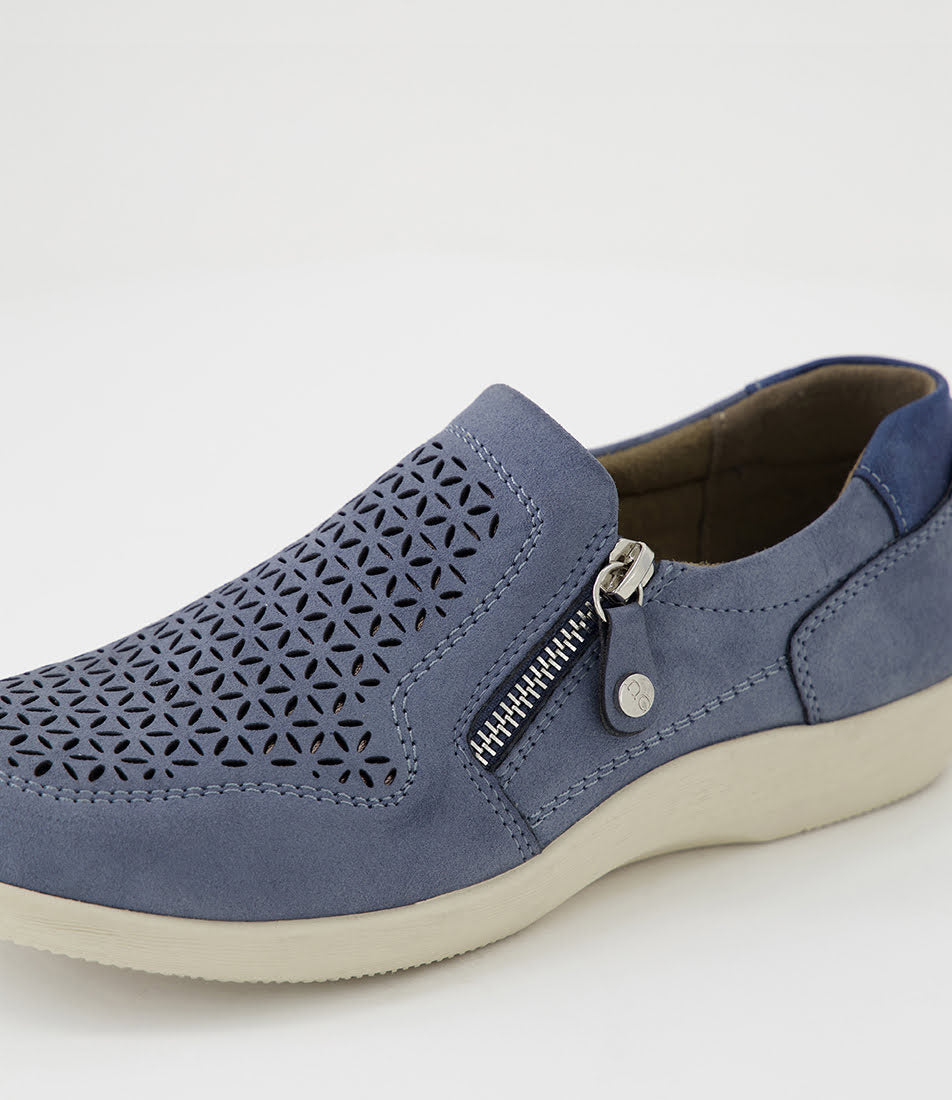 A blue slip-on shoe with a geometric laser-cut pattern on the toe, a silver zipper on the side, and a thick cream-colored sole, shown against a plain white background.